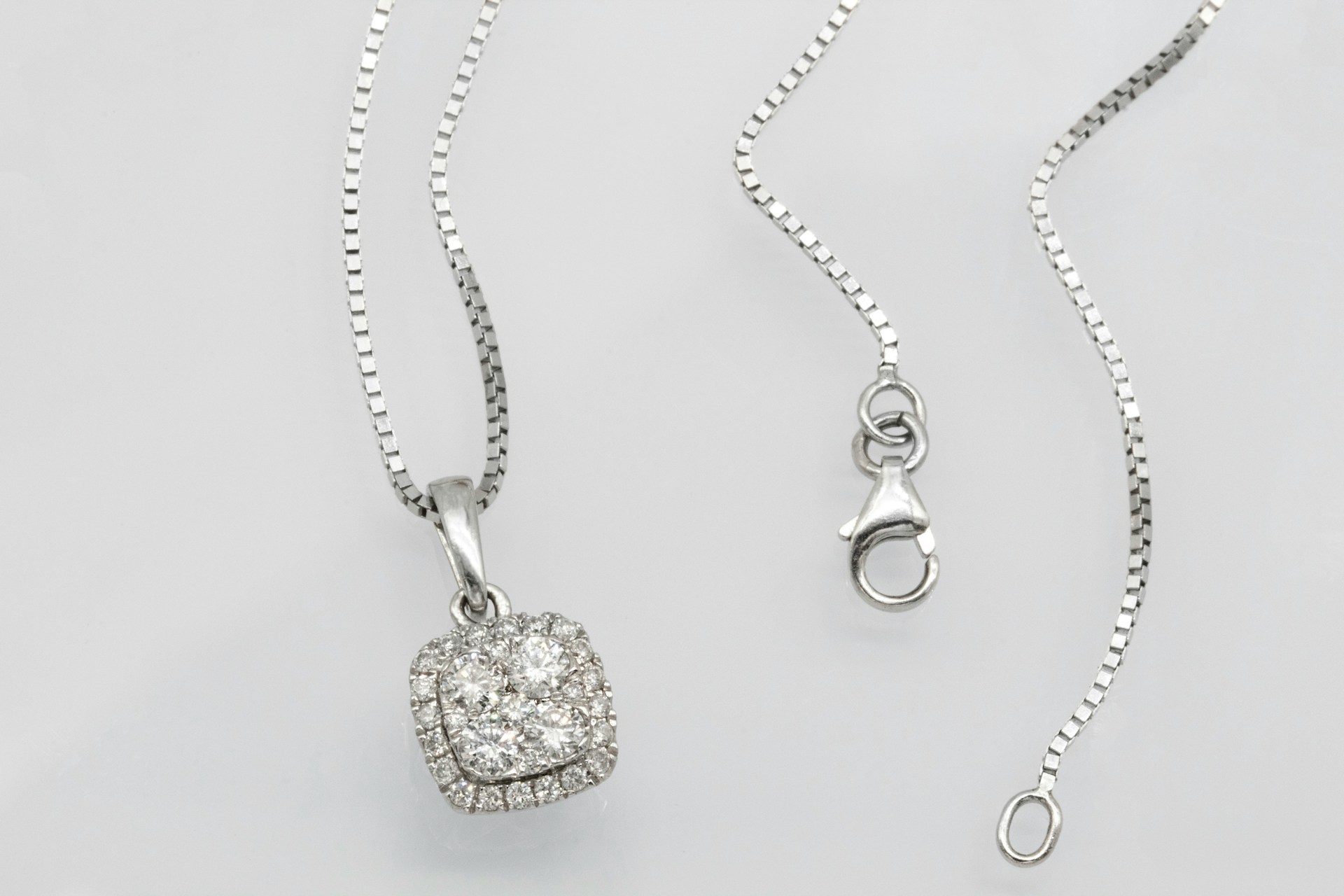 a silver pendant necklace featuring a diamond pendant surrounded by a halo of accent diamonds