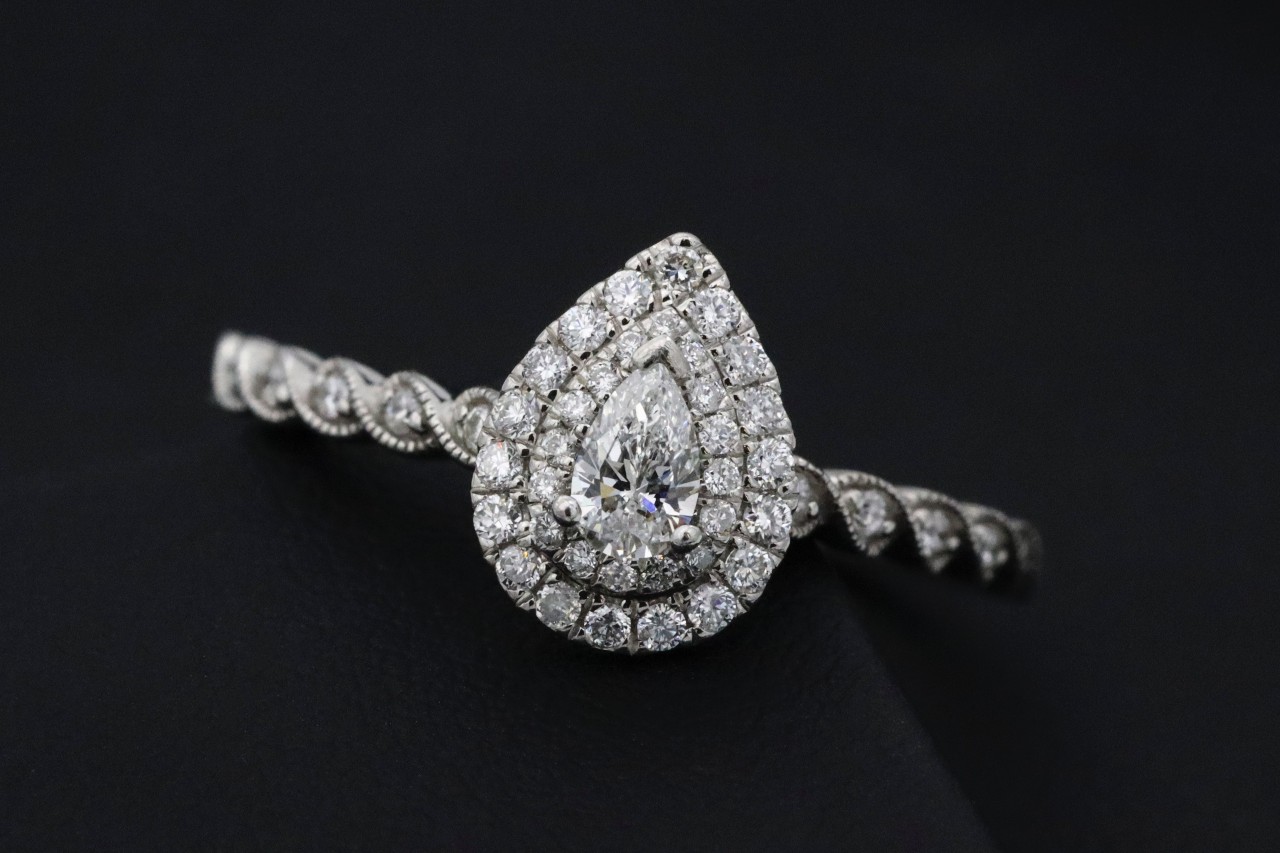 A platinum pear shape ring with a double halo and milgraining details on the shank.