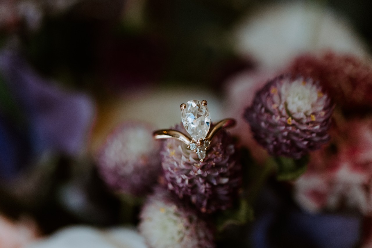A yellow gold pear-shape ring sits on a blossom in a floral arrangement.