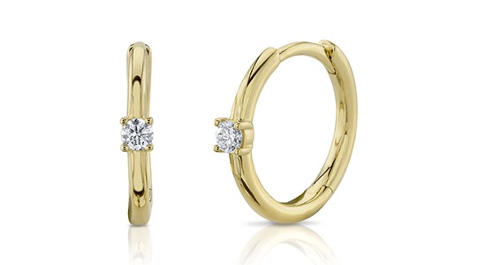 a pair of yellow gold huggies earrings, each featuring a solitary diamond
