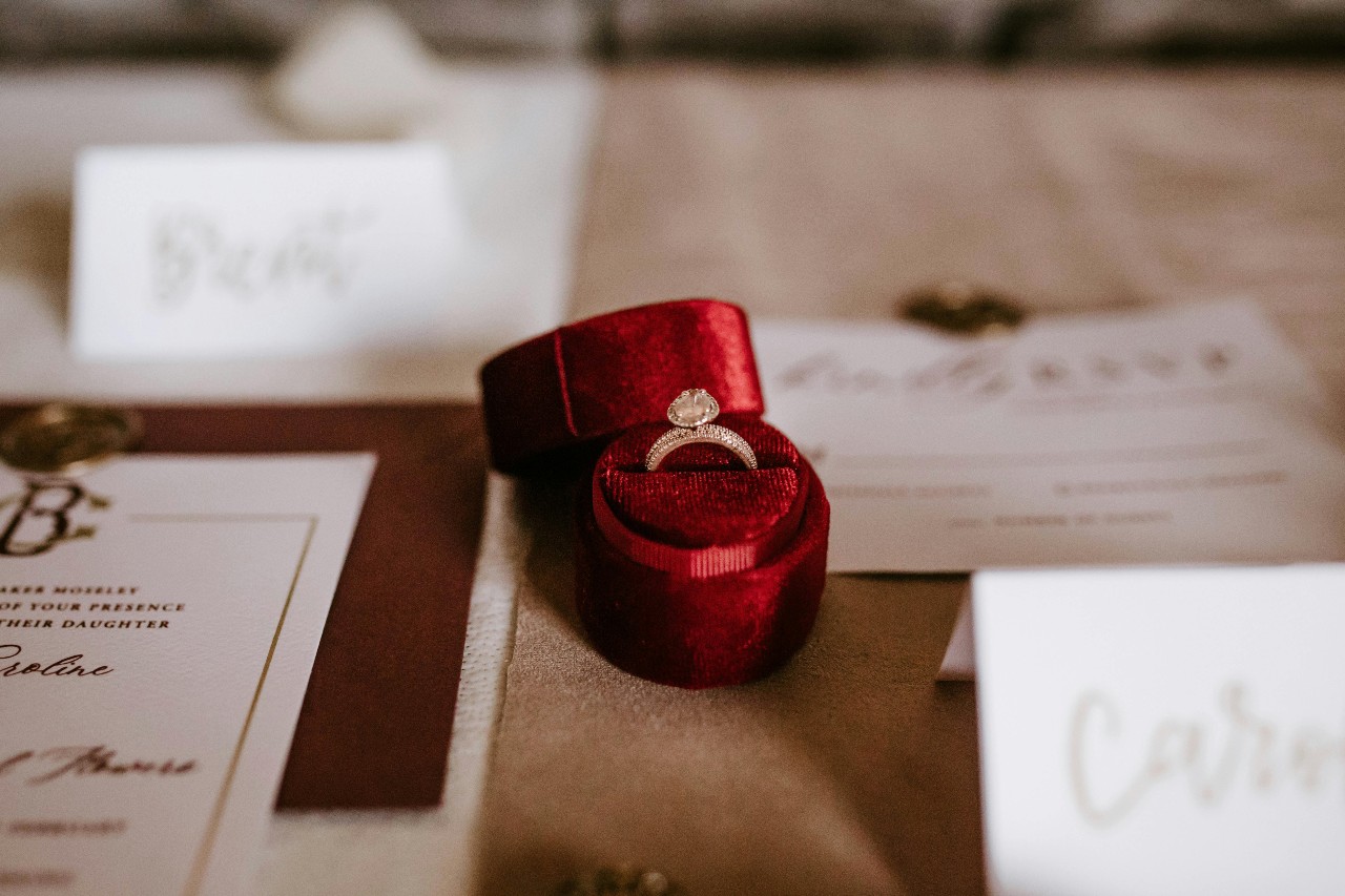 an engagement ring in a red box on a table with name tags for a wedding