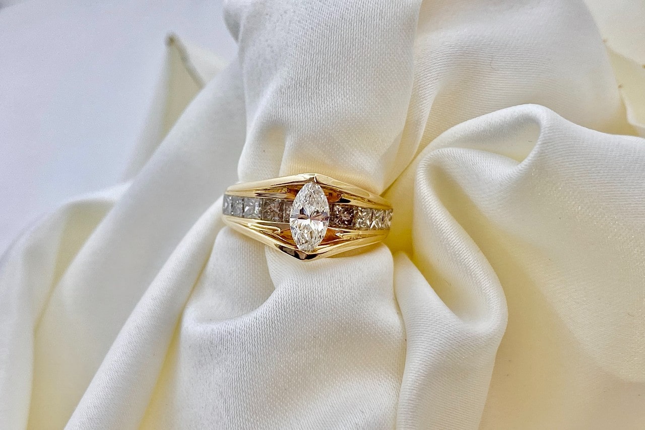 a yellow gold diamond engagement ring wrapped around a white cloth