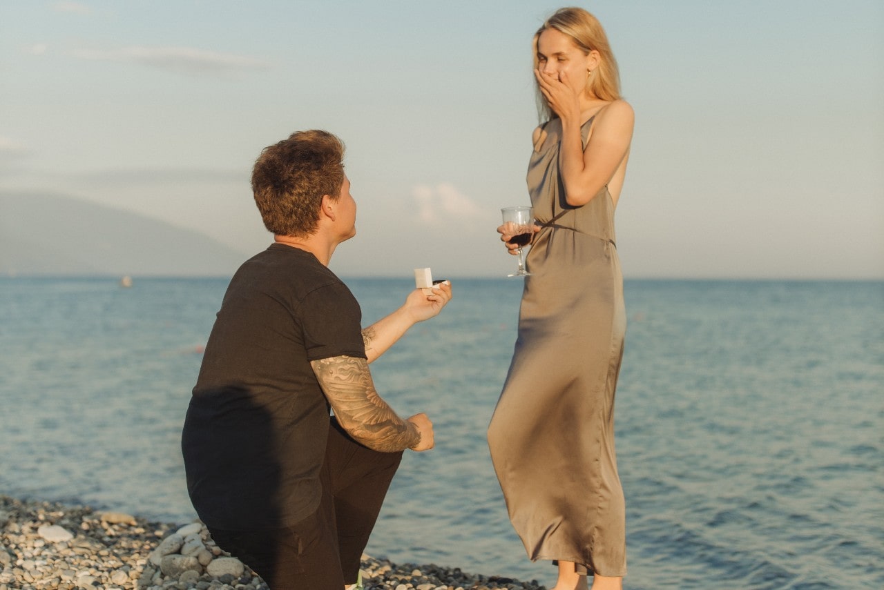 Man proposing to a woman on a beach.