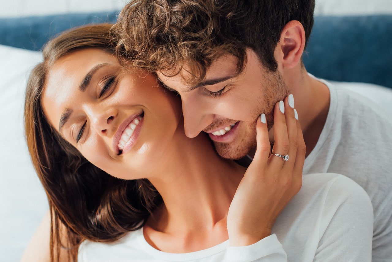 Man and woman smiling in embrace.