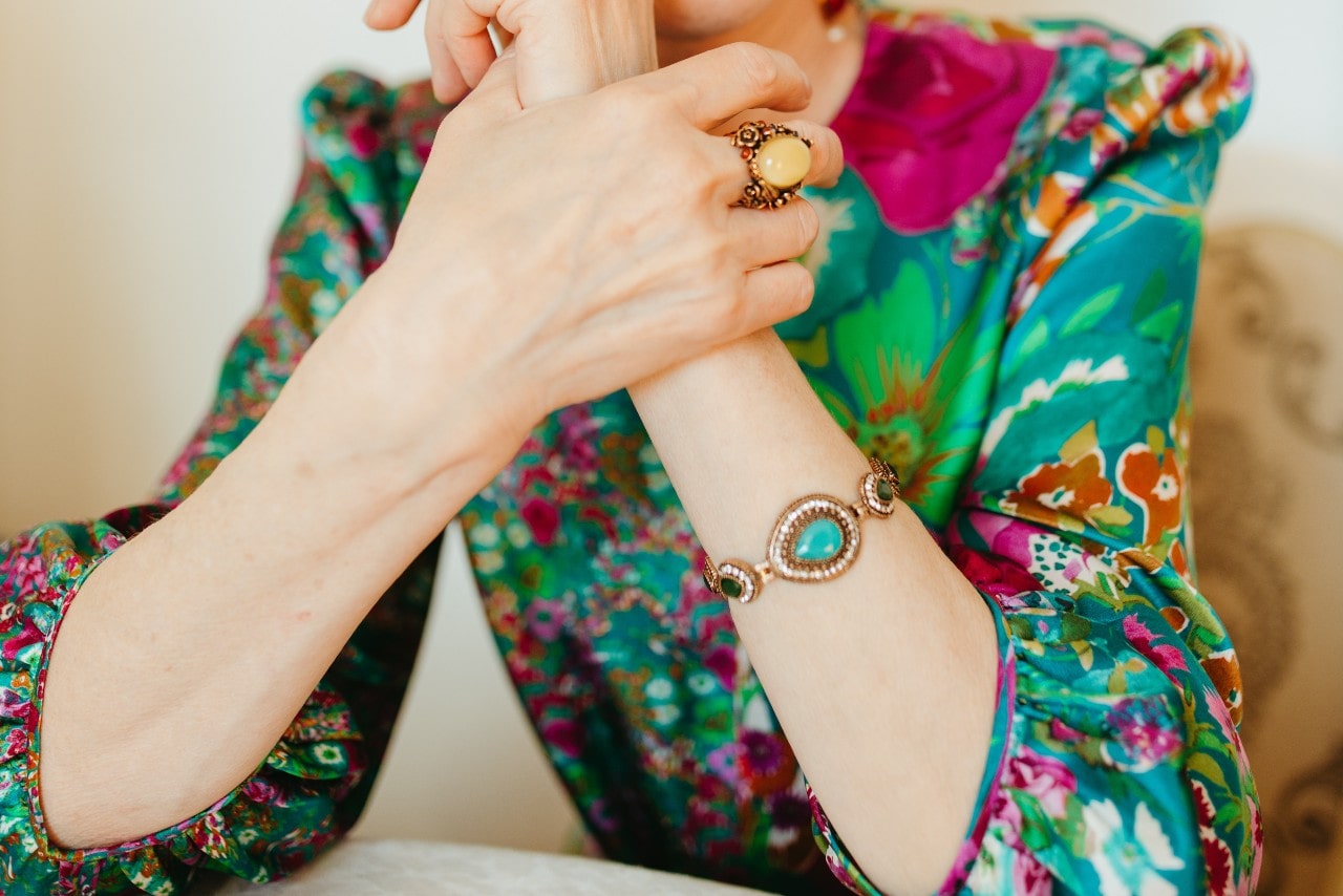 lady’s torso and arms in colorful clothes wearing a fashion ring and bracelet