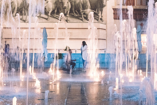 a woman being proposed to behind a brightly lit fountain display