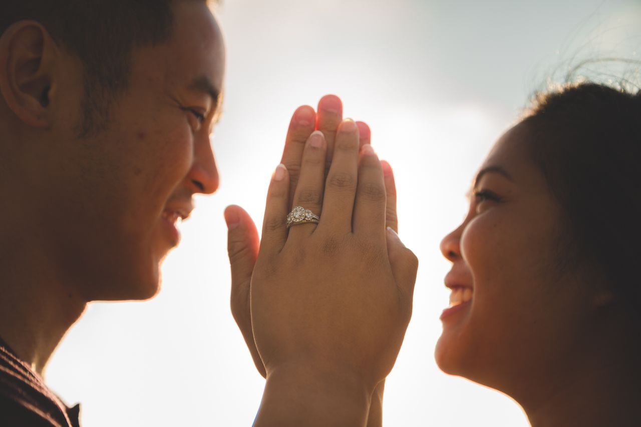 couple holding hands with three stone halo ring