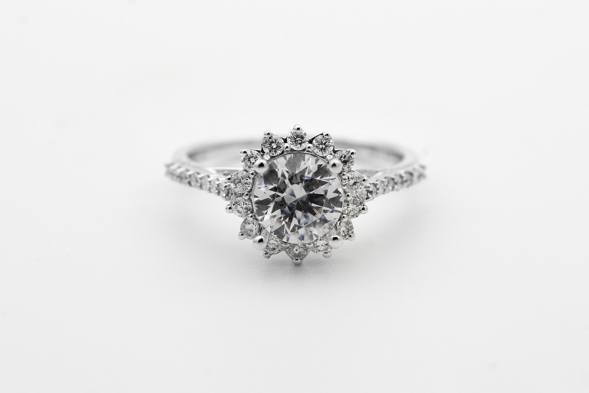 a white gold halo engagement ring with a round cut center stone and a floral silhouette