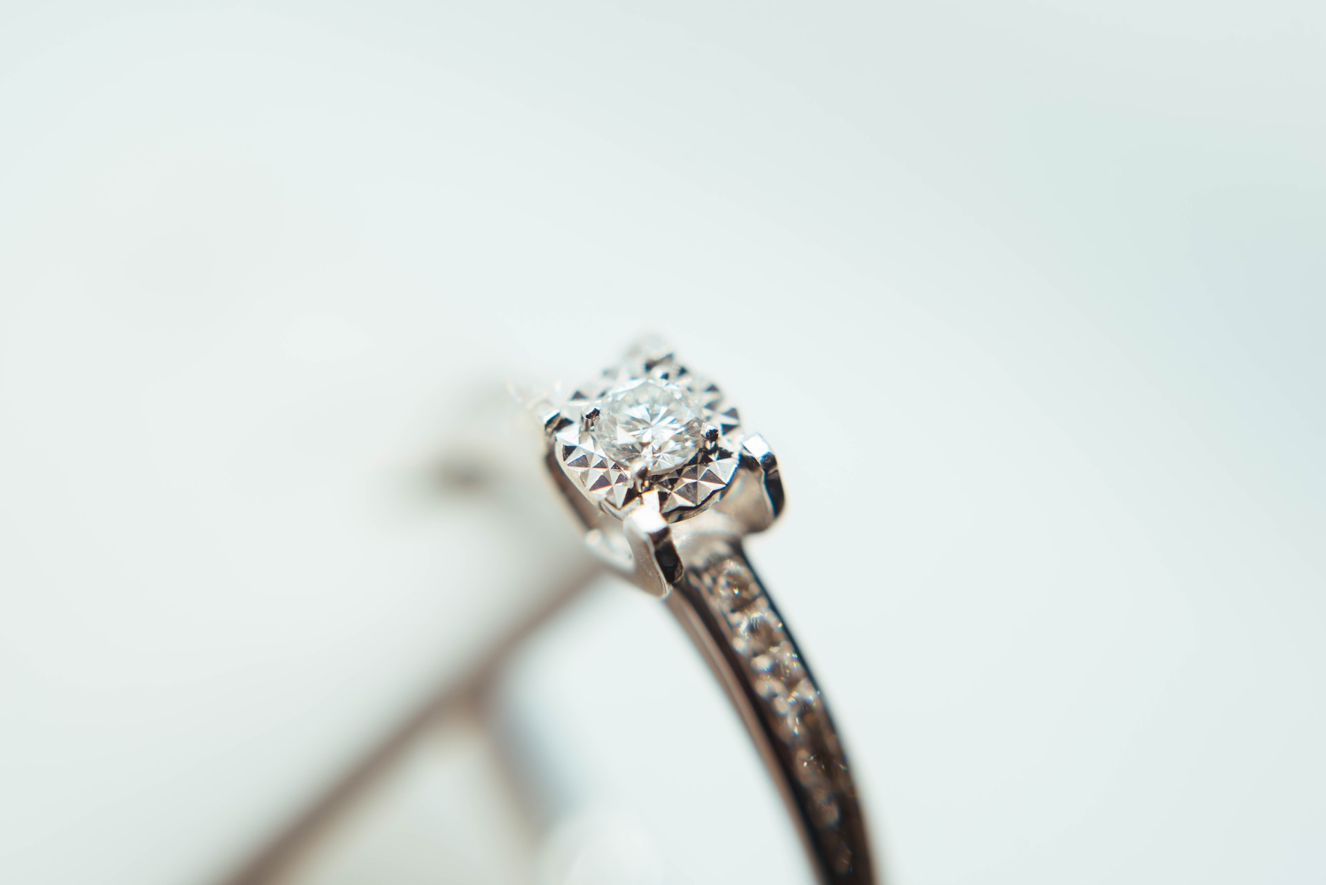 close up image of a white gold engagement ring featuring a round cut center stones and side stones